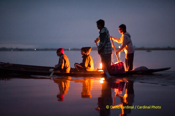 Inthar fishermen warming themselves before dawn with a fire in their wooden boat, pre-dawn on Inle Lake, Myanmar, Cardinal Photo tour.